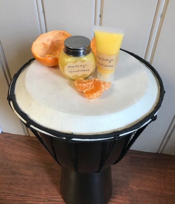 potje en tube met zelfgemaakte manderijnhandcreme en stukjes manderijn