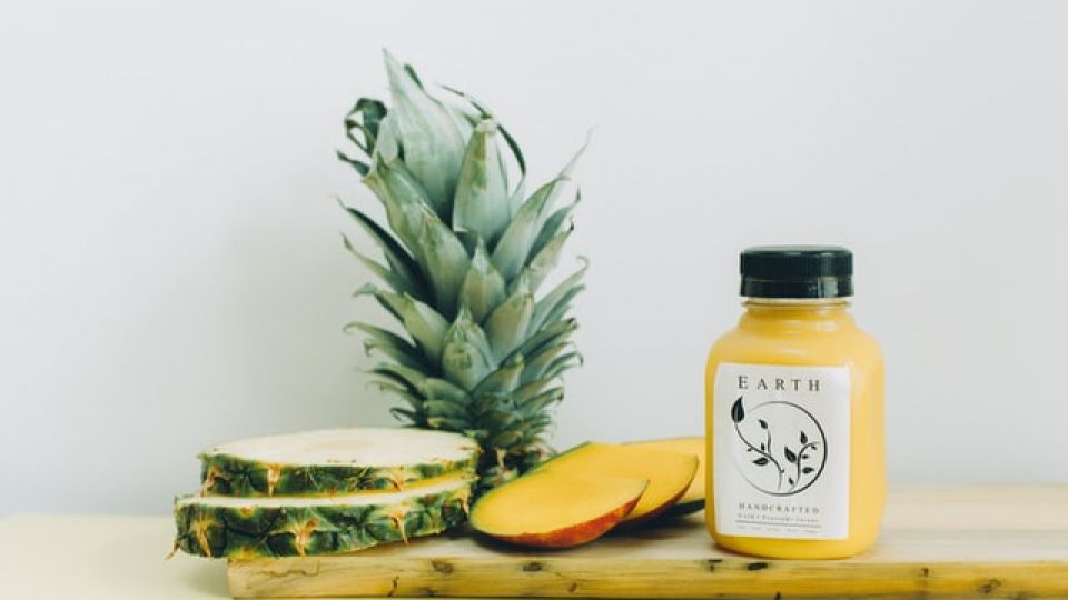 ananas en mango gesneden en potje op houten plank